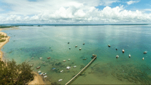 Vista aérea da Praia de Barra Grande, na Península de Maraú (Bahia), mostrando águas transparentes, barquinhos e um pier — fotografia de Márcio Filho – MTUR.