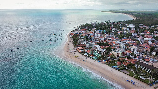 Vista aérea da Praia do Centro de Porto de Galinhas, com águas cristalinas, piscinas naturais e coqueiros; fotografia de Sitenl.
